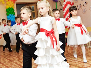 Маленькие дети танцуют на выпускном балу в садике